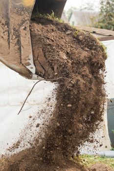 A bulldozer pours out a bucket of land on a construction site close-up. Excavation industrial work.