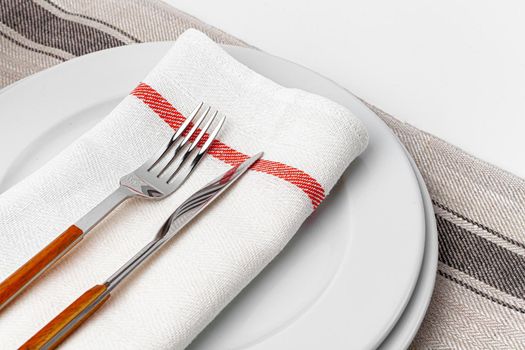 Fork, knife and plate on towel. Isolated on white background. Close up.