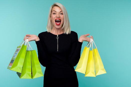 Sale. Young smiling woman holding shopping bags in black friday holiday. Happy Girl on blue background