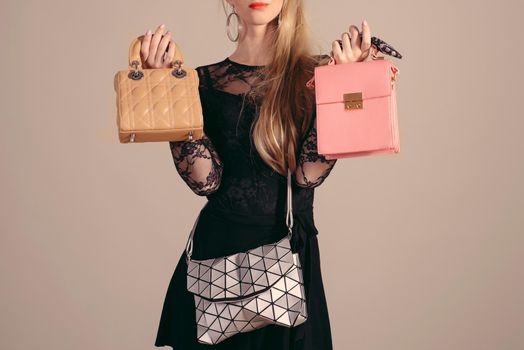 Young woman posing in black dress and three hand bag.