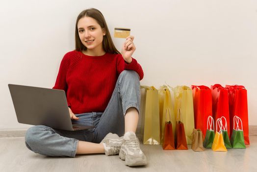 Young woman doing online shopping at home using laptop. Happy satisfied customer with purchase