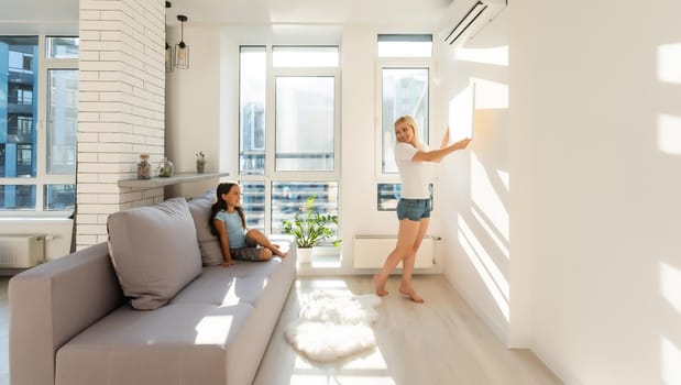 mother and daughter hangs a large photo canvas at home