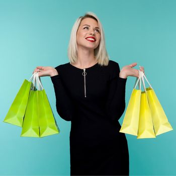Sale. Young smiling woman holding shopping bags in black friday holiday. Happy Girl on blue background
