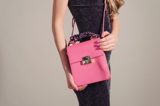 trendy woman in Evening Dress with pink bag in hands gray background