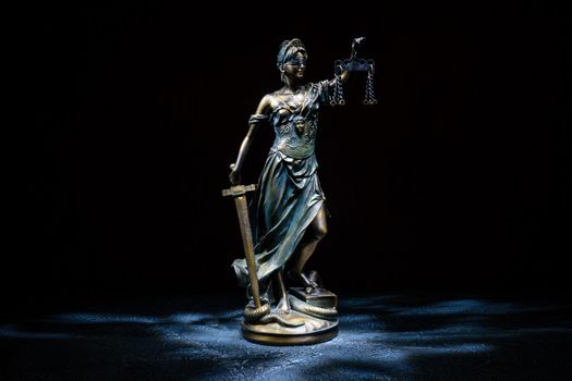 Themis statuette stands on the old vintage stone table. Picture taken with a light brush - Image