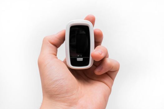 Man's hand holds medical modern pulse device oximeter close-up on white background.