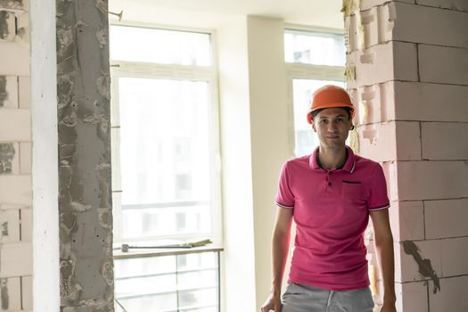 profession, construction and building - happy smiling worker or builder in helmet over room with working equipment at new home or apartment background