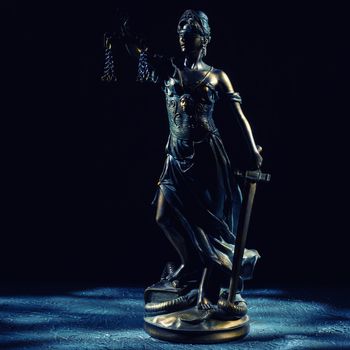 Themis statuette stands on the old vintage stone table. Picture taken with a light brush - Image toned