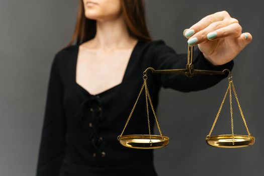 Serious woman holding the justice scale on dark background - image