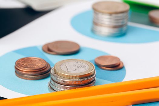 pile of money coins with graph paper on wood table, concept in account, finance and growth of business