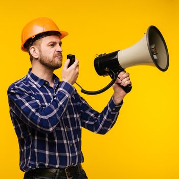 Angry worker man in orange helmet with a megaphone on yellow background - Image