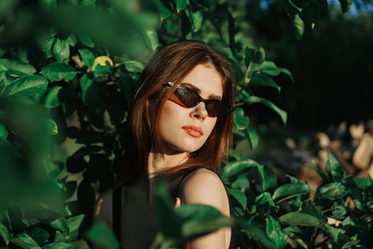 pretty woman wearing sunglasses green leaves posing summer. High quality photo