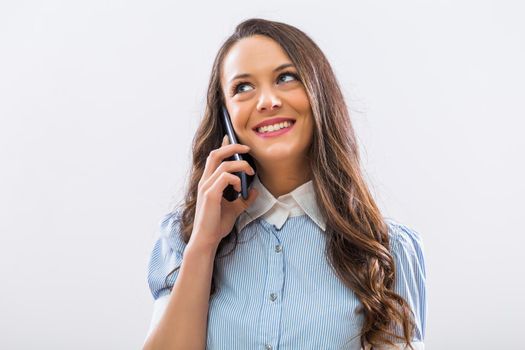 Image of beautiful businesswoman using phone on gray background.