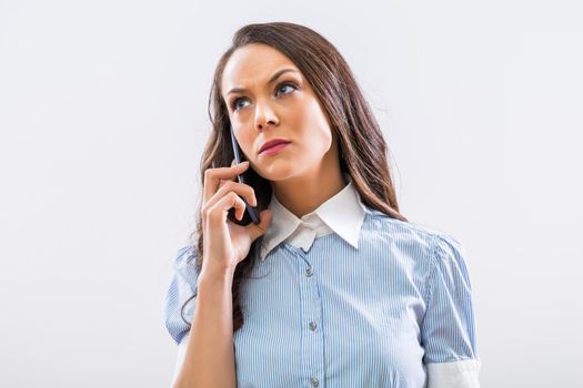 Image of angry businesswoman on the phone on gray background.