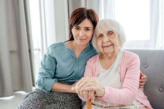 Senior woman and her young daughter girl hugging each other and looking at the camera. Grandmother with granddaughter family portrait