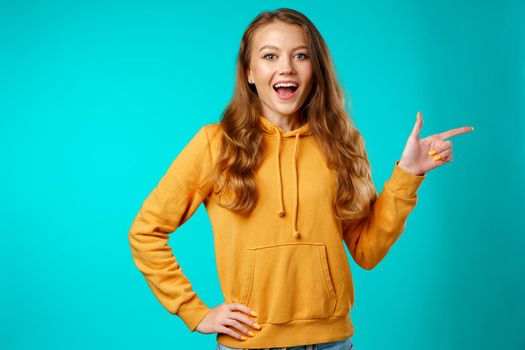 Portrait charming pretty cheerful girl showing copy space with her finger