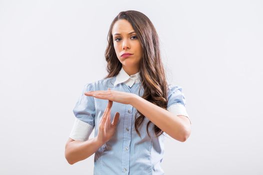 Image of tired businesswoman showing time out sign on gray background.