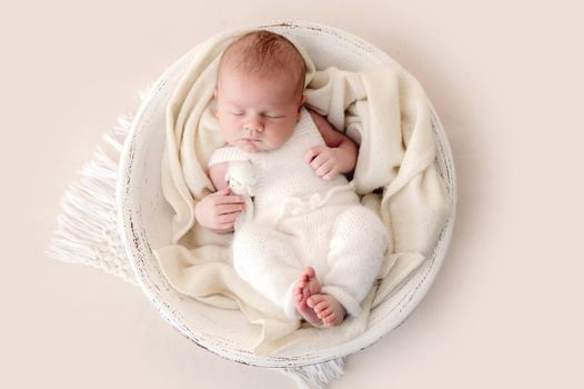 Newborn baby boy sleeping in designed basin. Adorable infant child kid napping during studio photoshoot