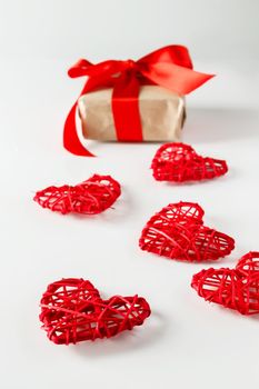 Valentine's day gift and red hearts on a white background. Valentine's Day gift on a background of red hearts from twigs of twigs, vertical photo