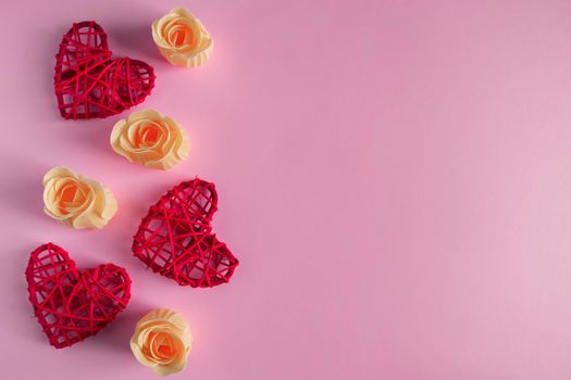 Red hearts and orange rosebuds on a pink background. Concept for Valentine's Day. Place for text.