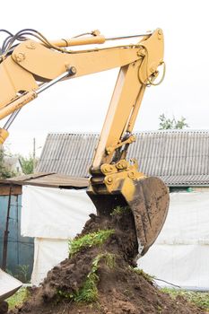 Excavation industrial work. A bulldozer pours out a bucket of land on a construction site close-up.