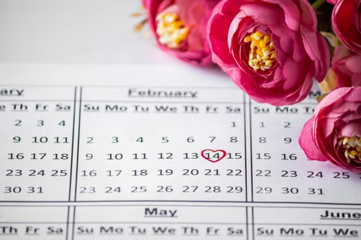 Calendar Reminder close up - Valentine's Day February 14th. Date in a red circle closeup on a background of flowers. Selective focus