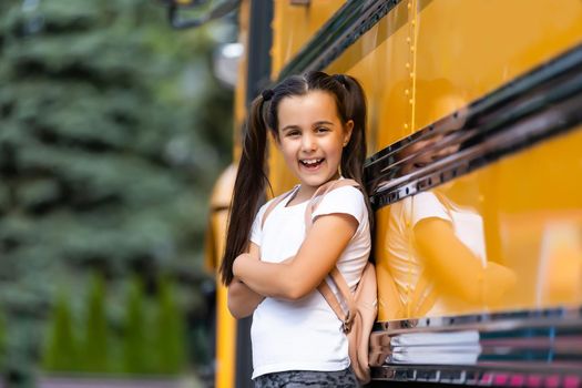 Girl with backpack near yellow school bus. Transport for students