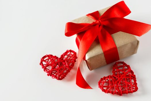 Valentine's day gift and red hearts on a white background. Valentine's day surprise with red ribbon and 2 hearts close-up on a white background