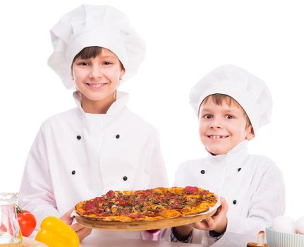 two smiling little cooks portioning fresh cooked pizza