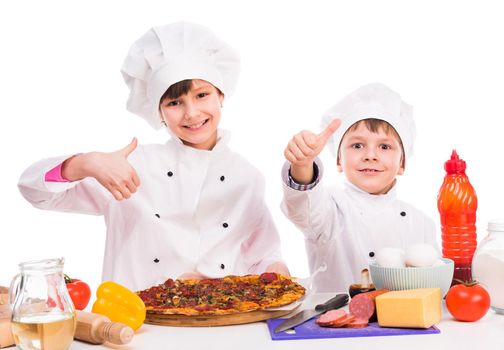 two smiling little cooks portioning fresh cooked pizza with thumbs up