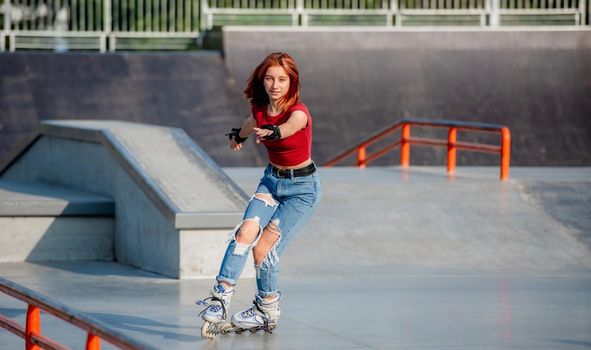 Pretty girl on roller skates practicing riding at park ramp. Female teenager rollerblading in the city at summer