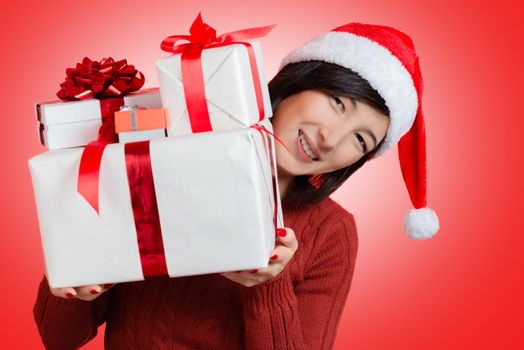 Beautiful young woman is holding many gifts on a red background