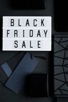 Black Friday online sale concept. Monochromatic flatlay on a dark background. Smartphone and accessories.