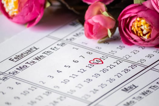 Calendar Reminder close up - Valentine's Day February 14th. Date in a red circle closeup on a background of flowers. Selective focus