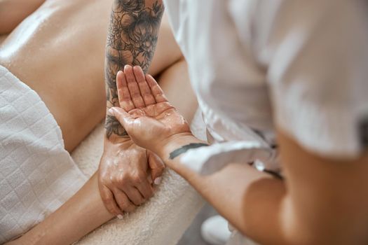 Professional confident massage master is doing procedures to caucasian woman in minimalistic modern cabinet