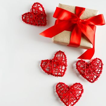 Valentine's day gift and red hearts on a white background. Holiday gift with red ribbon and craft paper on a white background. Valentine's Day hearts, place for your text.
