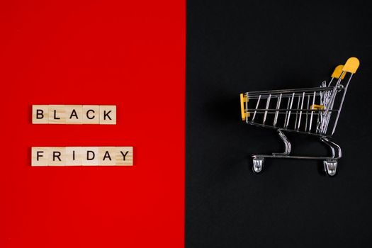 Black Friday sale concept. Mini shopping cart and sign on a red background. Banner for advertising.