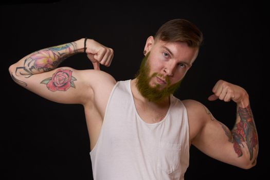 bearded man with tattoos on his arms gesturing with his hands dark background. High quality photo