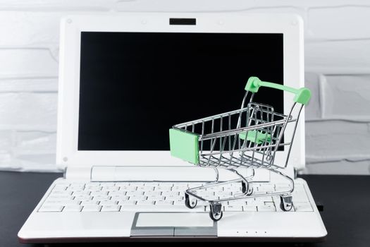 Black Friday concept. Mini shopping cart and laptop. Online sale and discounts.