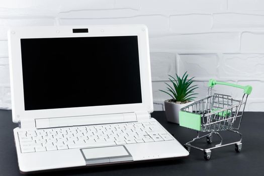 Black Friday concept. Mini shopping cart and laptop. Online sale and discounts.