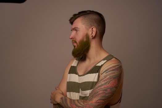 bearded man in striped t-shirt with tattoos posing studio. High quality photo