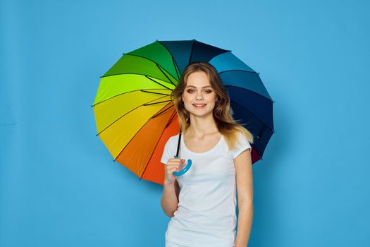 fashionable woman with umbrella rainbow colors posing blue background. High quality photo