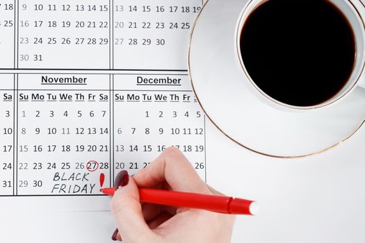 Black Friday November 27th. Woman notes a reminder on the calendar. Sale and discounts.