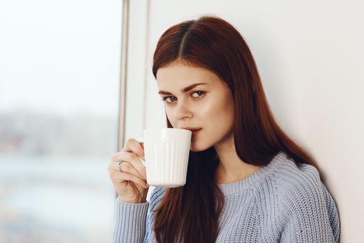 woman reading a book near the window with a cup of drink rest. High quality photo