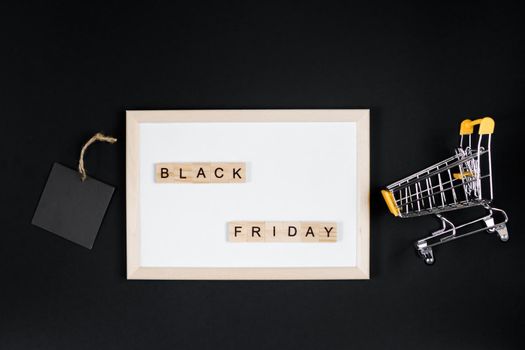 Black Friday sale. Mini shopping cart in frame on a black background. Banner for advertising.