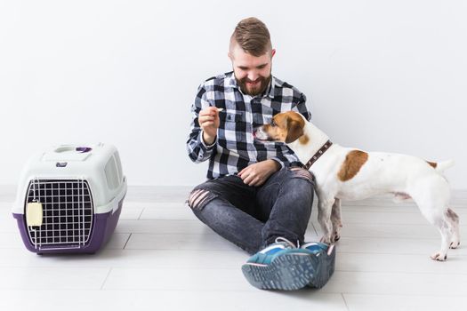 Dog carrying bags and pets owner concept - Attractive cheerful male in plaid shirt holds favourite pet. Happy bearded man with his jack russell terrier.