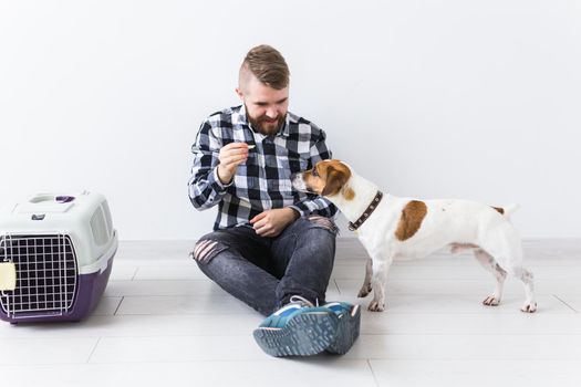 Dog carrying bags and pets owner concept - Attractive cheerful male in plaid shirt holds favourite pet. Happy bearded man with his jack russell terrier.