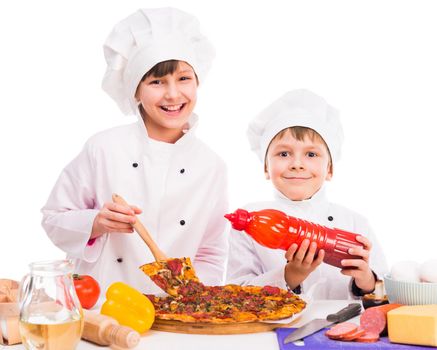 two smiling little cooks portioning fresh cooked pizza