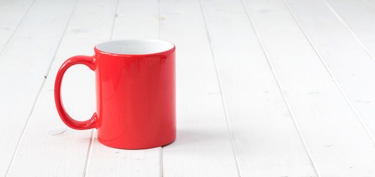 red cup with white inside on white wooden table