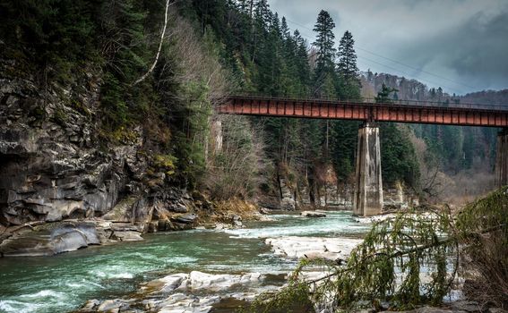 landscape in Carpathian mountains with river, railway bridge